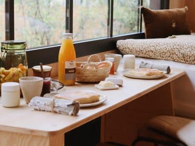 Un hébergement insolite avec une vue panoramique, petit-déjeuner copieux sur une table en bois.