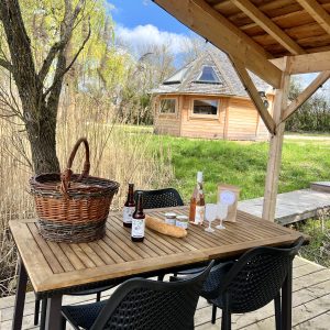 Un chalet en bois avec une terrasse accueillante, table en bois et panier pique-nique.