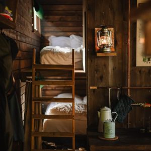 Cabane en bois chaleureuse avec lits superposés et ambiance rustique, éclairée par une lampe à