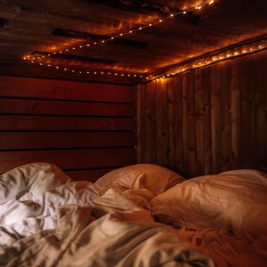 Chambre cocooning en bois, éclairée par des guirlandes lumineuses, ambiance chaleureuse.