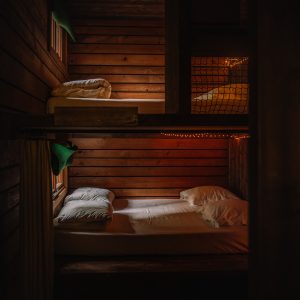 Cabane en bois avec lits superposés, ambiance chaleureuse et éclairage tamisé.