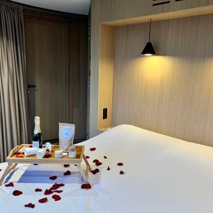 Chambre romantique avec lit décoré de pétales de rose et plateau de champagne.