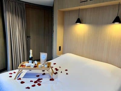 Chambre romantique avec lit décoré de pétales de rose et plateau de champagne.