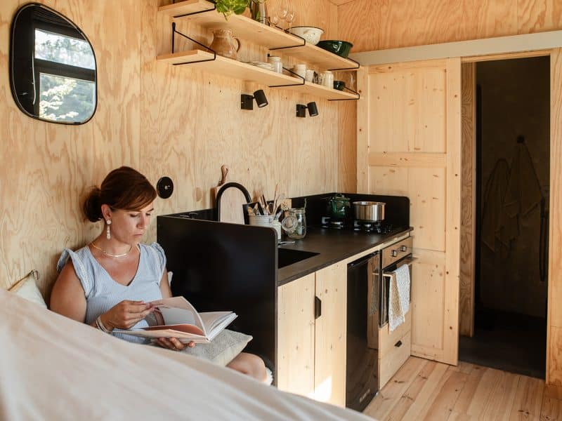 Tiny house en bois avec cuisine équipée, ambiance chaleureuse et lumineuse.
