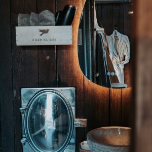 Salle de bain d'un hébergement insolite, avec un lavabo en pierre et un miroir oval.