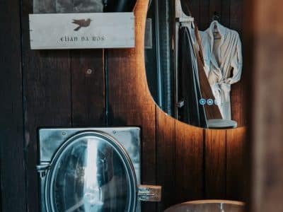 Salle de bain d'un hébergement insolite, avec un lavabo en pierre et un miroir oval.