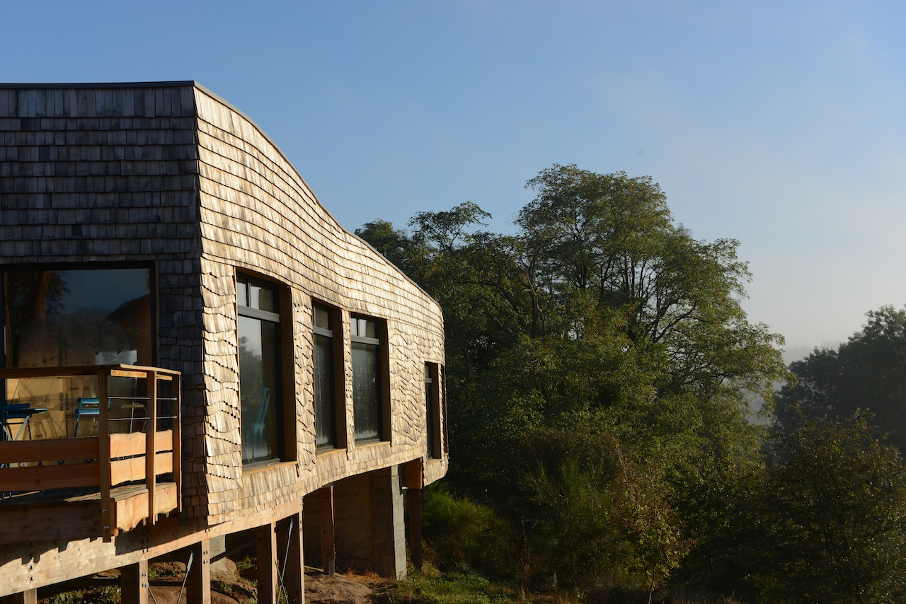 Cabane en bois sur pilotis, avec vue dégagée sur la nature environnante.