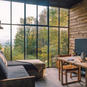 Cabane moderne avec grandes fenêtres, offrant une vue imprenable sur la nature environnante.