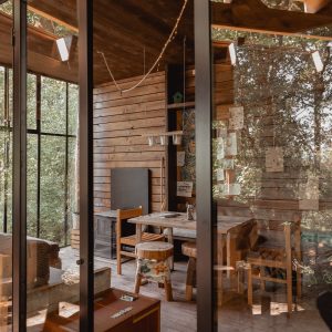 Cabane moderne en bois avec grandes fenêtres, offrant une vue sur la nature environnante.