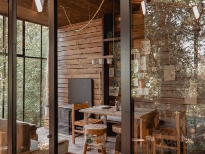 Cabane moderne en bois avec grandes fenêtres, offrant une vue sur la nature environnante.