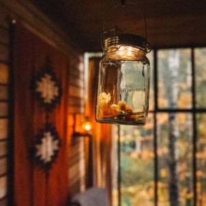 Un chalet cosy avec une lampe en verre suspendue, ambiance chaleureuse et nature environnante.