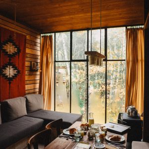 Un chalet en bois avec de grandes fenêtres, offrant une vue sur la nature et un petit-déjeuner