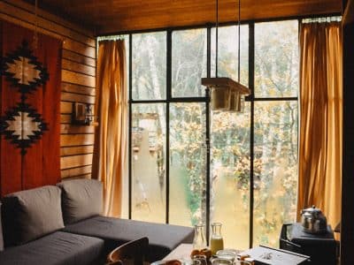 Un chalet en bois avec de grandes fenêtres, offrant une vue sur la nature et un petit-déjeuner