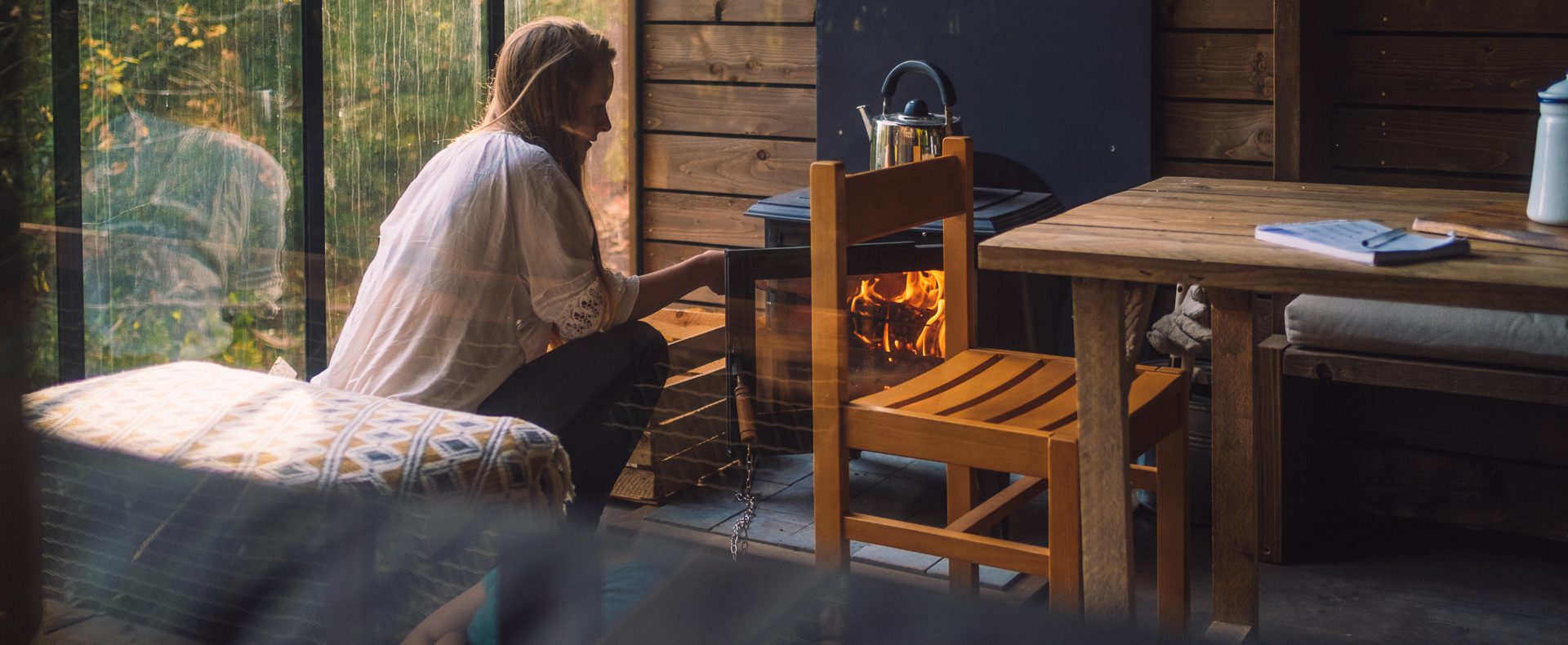 Cabane en bois avec poêle à bois, ambiance chaleureuse et vue sur la nature.