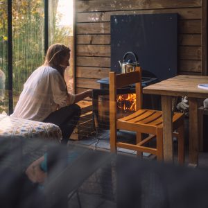 Cabane en bois avec poêle à bois, ambiance chaleureuse et vue sur la nature.