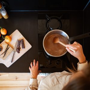 Cuisine moderne avec une casserole de chocolat chaud, agrémentée de fruits et épices.