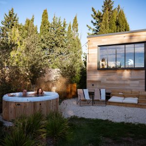 Hébergement insolite : chalet en bois avec jacuzzi extérieur, entouré de verdure.