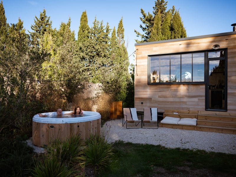 Chalet moderne avec jacuzzi extérieur, entouré de verdure apaisante.