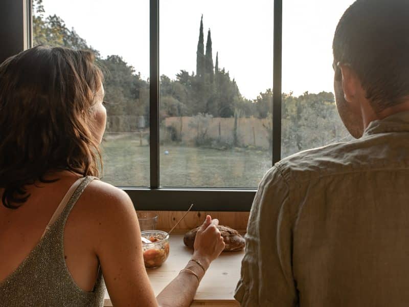 Vue romantique depuis un chalet, couple admirant le coucher de soleil.