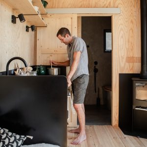 Tiny house moderne avec intérieur en bois, cuisine fonctionnelle et poêle à bois.