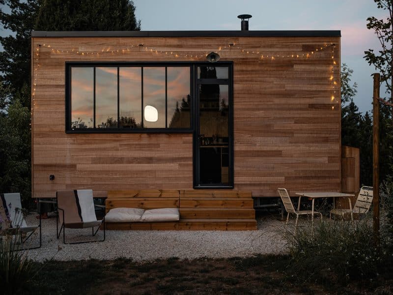 Cabane en bois moderne avec éclairage extérieur et terrasse accueillante.