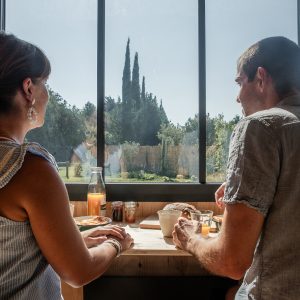 Un couple savourant un petit-déjeuner dans un hébergement moderne avec vue sur la nature.