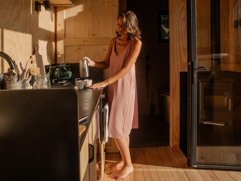Cabane moderne avec cuisine en bois, lumière naturelle et ambiance chaleureuse.