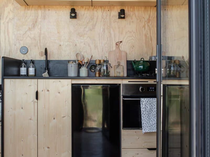 Cuisine moderne dun chalet en bois, avec étagères et plantes décoratives.