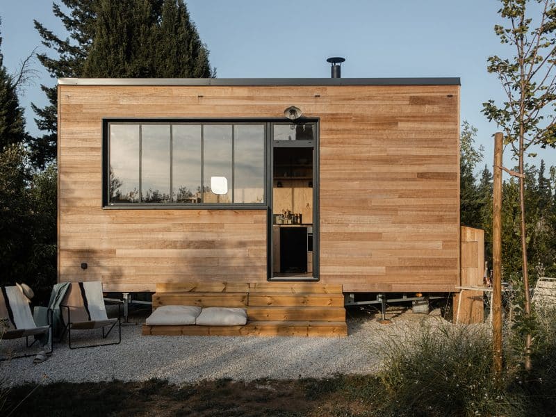 Tiny house en bois avec grande fenêtre et terrasse accueillante.