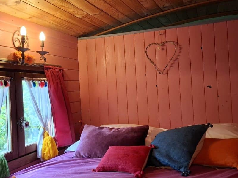 Chalet romantique avec murs roses et coussins colorés, ambiance chaleureuse et accueillante.