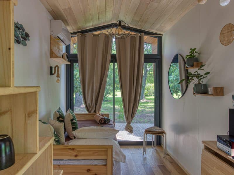 Chalet moderne avec grandes fenêtres, offrant une vue sur la nature verdoyante.