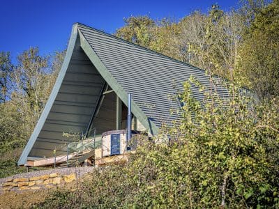 Hébergement insolite en Bourgogne : chalet moderne avec toit en pente, entouré de verdure.