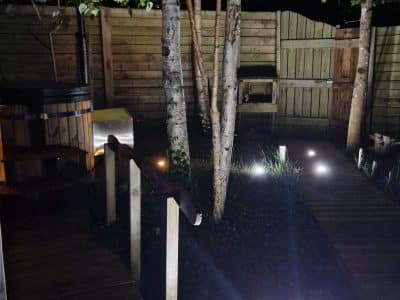 Hébergement insolite en Hauts-de-France avec un jacuzzi en bois et un chemin lumineux.
