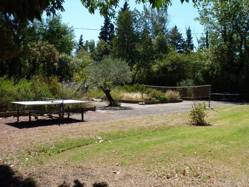 Gîte rural avec terrain de pétanque et verdure luxuriante autour.