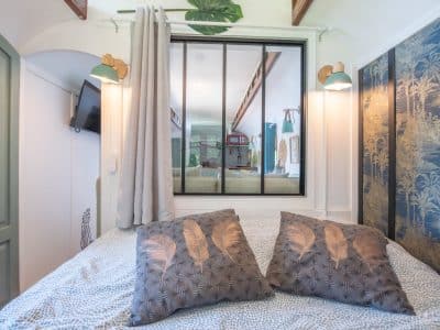 Chambre cosy dans un hébergement insolite, décorée de coussins à motifs de plumes.
