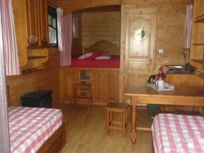 Hébergement insolite en Bretagne : roulotte en bois avec lits à rayures et coin cuisine.