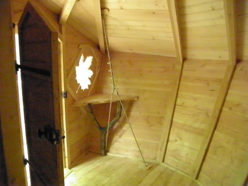 Cabane en bois avec un intérieur chaleureux et une fenêtre en forme de feuille.