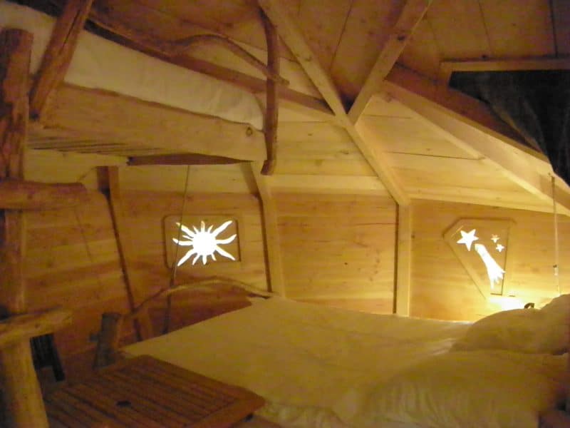 Chalet en bois avec lit superposé et fenêtres décoratives en forme détoiles.
