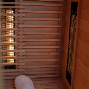 Vue rapprochée de l’intérieur d’un sauna infrarouge en bois avec une serviette roulée