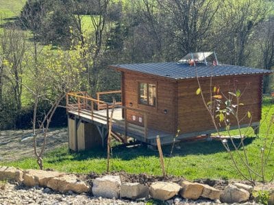 Cabane en bois avec terrasse, entourée de verdure en Provence-Alpes-Côte dAzur.