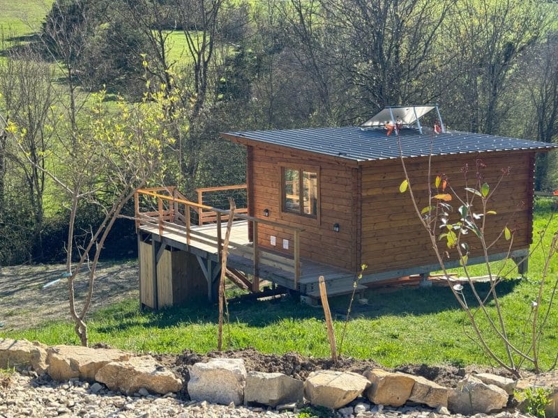 Chalet en bois avec terrasse, entouré de verdure et de paysages naturels.