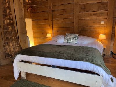 Chalet en bois chaleureux avec lit douillet et éclairage tamisé. Parfait pour un séjour relaxant.
