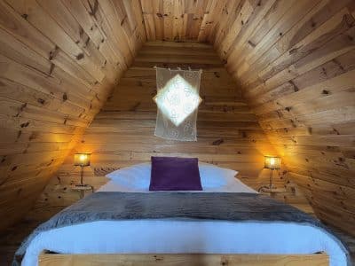 Chalet en bois avec lit douillet et éclairage chaleureux dans les Hauts-de-France.