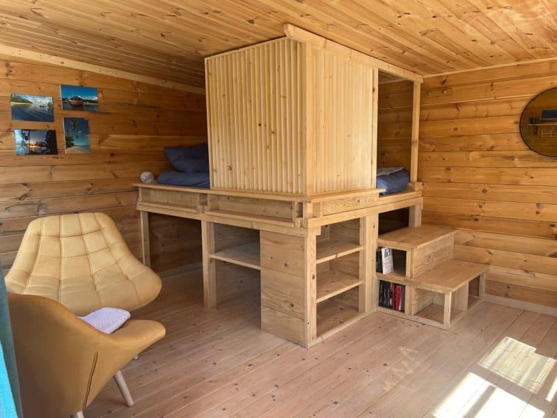 Cabane en bois avec lit surélevé et coin salon confortable.