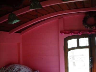 Cabane colorée en rose, avec un plafond en bois et une fenêtre charmante.