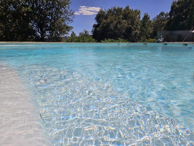 Hébergement touristique avec piscine claire, entourée de verdure et ciel bleu.
