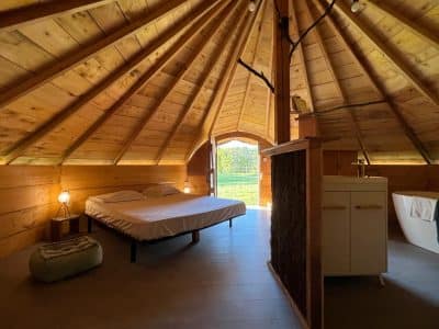 Hébergement insolite en yourte, intérieur en bois chaleureux avec vue sur la nature.