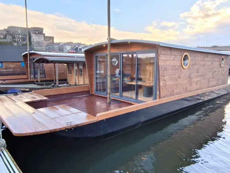 Hébergement insolite : maison flottante en bois avec grandes fenêtres sur leau.