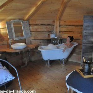 Cabane en bois avec baignoire vintage et ambiance chaleureuse.