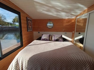 Chambre sur une péniche à Pays de la Loire, décor bois et vue sur leau.